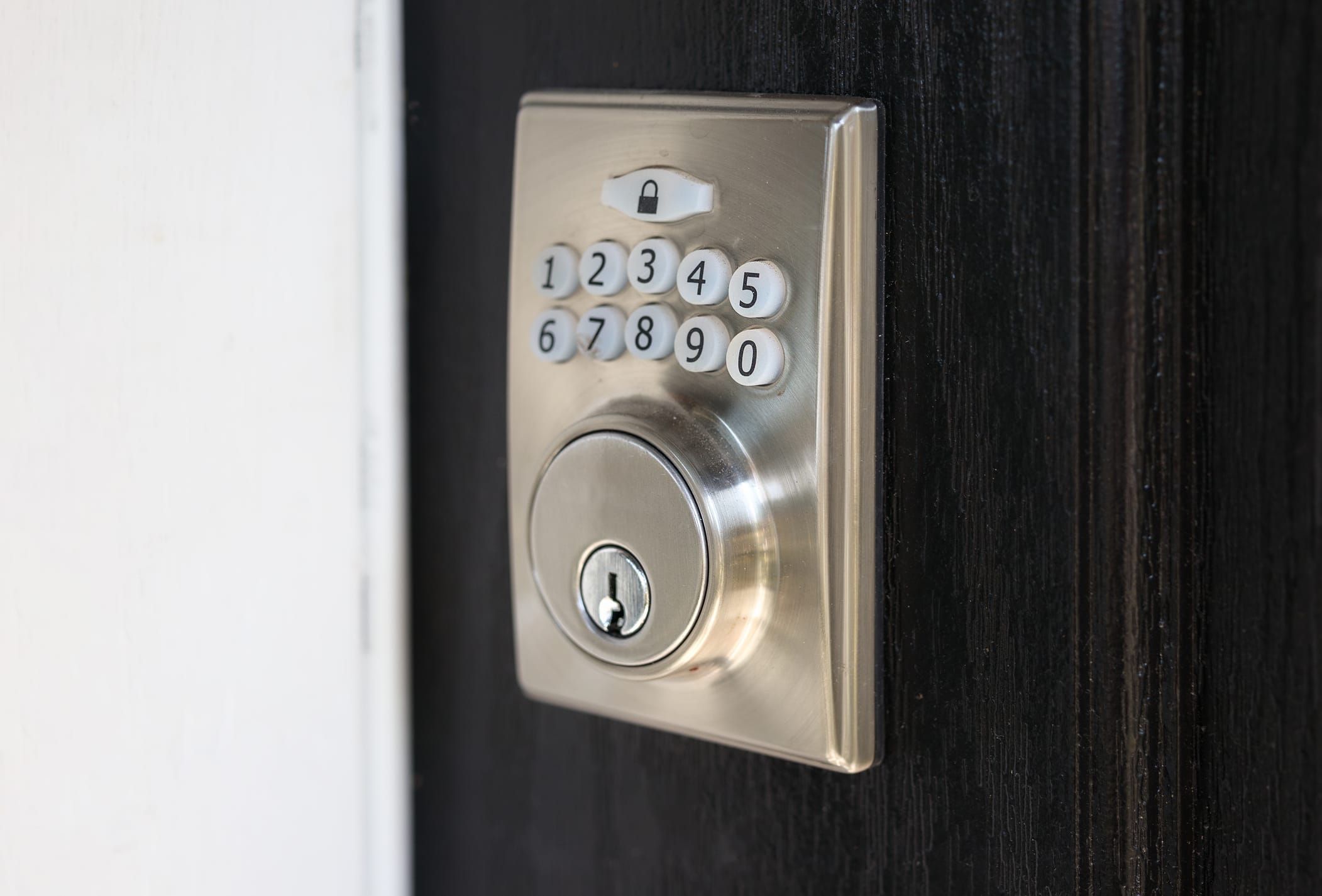 Close-up of a commercial deadbolt lock on a dark gray metal door, featuring a brushed nickel finish and secure strike plate. Ideal for office or industrial entry doors, highlighting commercial-grade security hardware.