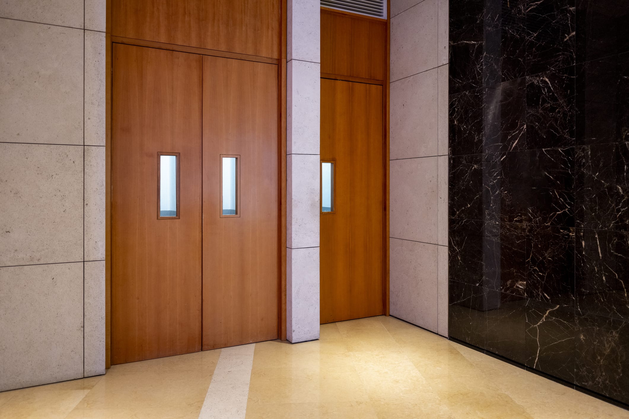 Industrial wood doors with narrow glass inserts in a commercial building hallway, designed for visibility and safety in high-traffic areas.